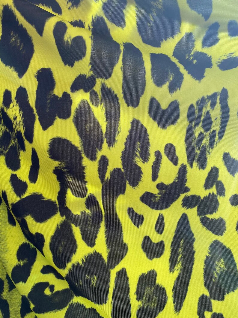 Puede incluir: Primer plano de una tela amarilla con un patr&oacute;n de estampado de leopardo negro.