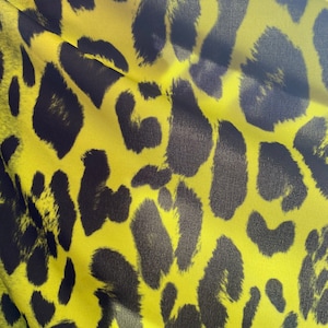 Puede incluir: Primer plano de una tela amarilla con un patr&oacute;n de estampado de leopardo negro.
