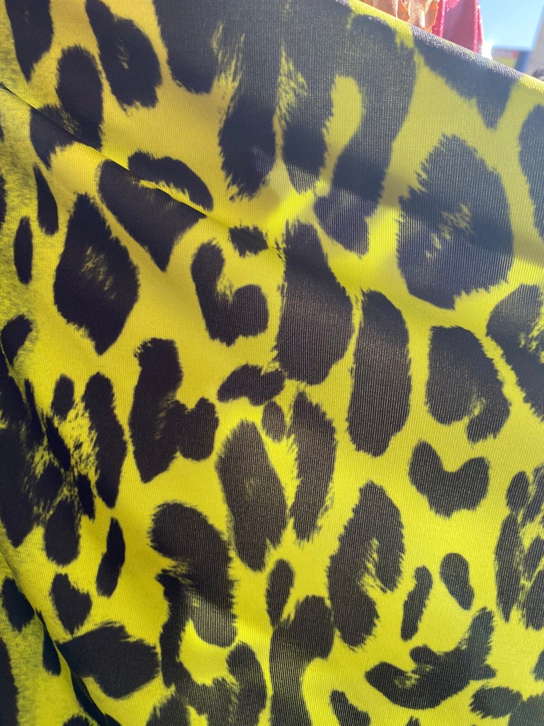 Puede incluir: Primer plano de una tela amarilla con un patr&oacute;n de estampado de leopardo negro.