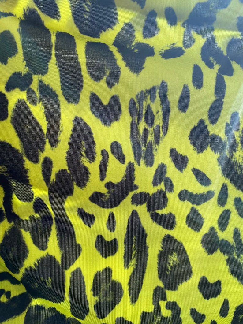 Puede incluir: Tela amarilla con estampado de leopardo negro.