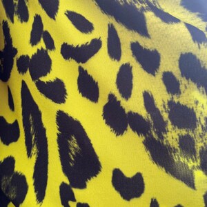 Puede incluir: Tela amarilla con estampado de leopardo negro.