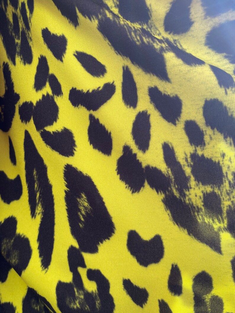 Puede incluir: Tela amarilla con estampado de leopardo negro.