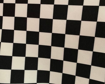 May include: Black and white checkered fabric with a slight wave pattern. The fabric is made of a smooth, silky material.