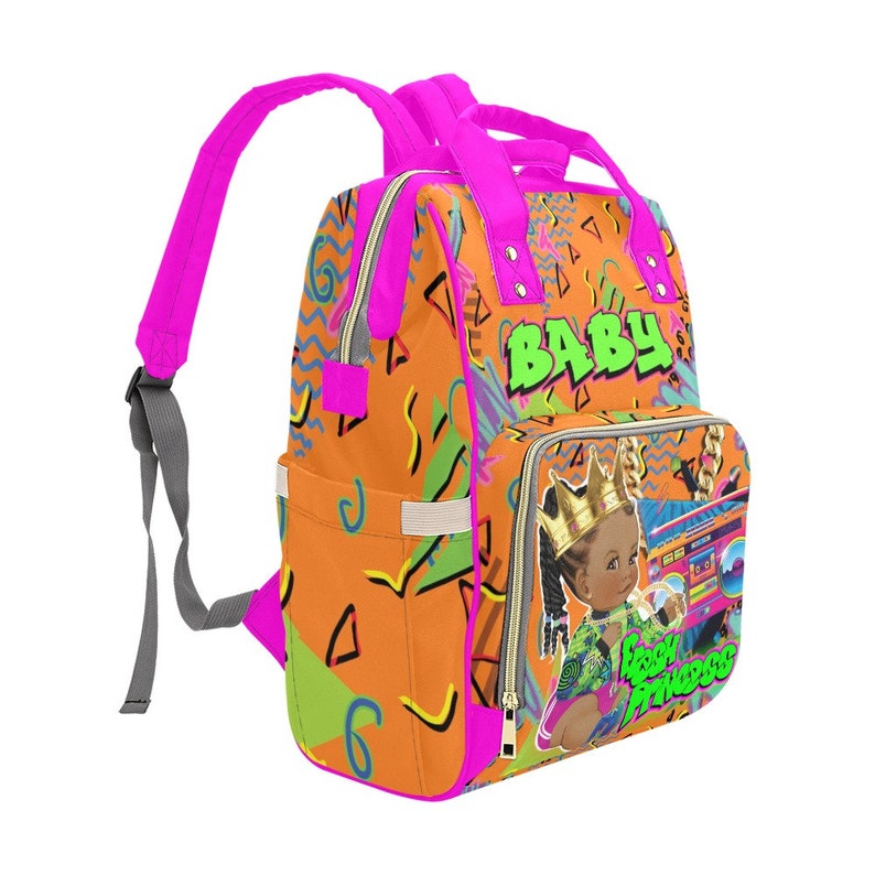 May include: A pink and orange backpack with a geometric pattern. The backpack has a large pocket on the front with a picture of a young girl wearing a crown and holding a boombox. The text "BABY" and "BLACK PRINCESS" are printed on the backpack.