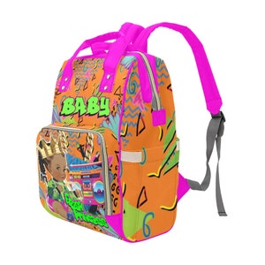 May include: A bright orange and pink nappy bag with a 90s style graphic print. The bag features a cartoon image of a young girl wearing a crown and holding a boombox. The text "Baby Princess" is printed on the bag.