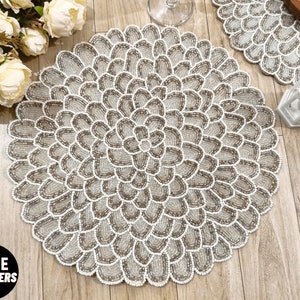 Könnte beinhalten: Ein runder, weißer und beigefarbener Perlen-Platzteller mit Blumenmuster. Der Platzteller besteht aus kleinen, runden Perlen, die in einem kreisförmigen Muster angeordnet sind. Der Platzteller ist perfekt, um jedem Esstisch einen Hauch von Eleganz zu verleihen.