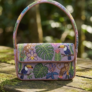 May include: A beaded handbag with a purple background and a brown handle. The bag features a tropical design with toucans, monkeys, and lush foliage. The handle and edges are brown.