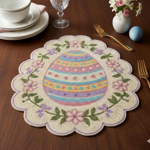 Peut inclure: Un set de table de Pâques avec un motif de perles. Le set de table présente un grand œuf de Pâques coloré au centre, entouré d'une bordure florale. L'œuf a des rayures horizontales aux couleurs pastel.