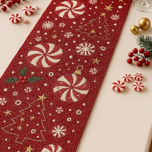 Puede incluir: Camino de mesa navideño rojo con cuentas con caramelos de menta blanca y roja, copos de nieve y un diseño de árbol de Navidad. Estrellas doradas y acentos de acebo completan el look festivo. Una pieza decorativa para la cena navideña.