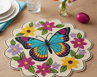 Puede incluir: Un mantel individual de cuentas con un diseño de mariposa y flores. La mariposa tiene alas turquesas, amarillas, rosas y negras. Las flores son amarillas, rosas y moradas con hojas verdes. El mantel individual es beige con un borde festoneado.