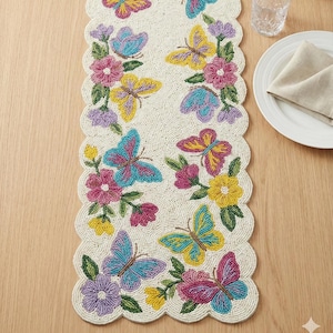 May include: Cream-coloured beaded table runner with a scalloped edge, decorated with colourful butterflies and flowers in pink, yellow, and blue. Suitable for decorative use on a table.