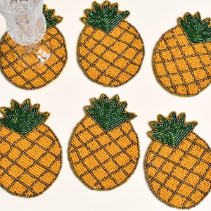 Puede incluir: Seis posavasos de cuentas de piña de color amarillo y verde. Los posavasos están hechos de cuentas pequeñas y tienen una superficie texturizada.