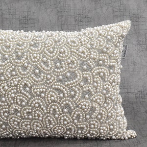 Puede incluir: Una funda de coj&iacute;n blanca con un dise&ntilde;o de perlas. La funda de coj&iacute;n est&aacute; hecha de una tela suave y lujosa y es perfecta para agregar un toque de elegancia a cualquier habitaci&oacute;n. La funda de coj&iacute;n est&aacute; adornada con una peque&ntilde;a etiqueta que dice "ZARMOON".