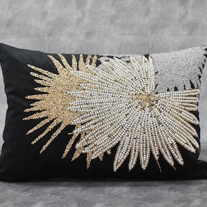 May include: Black velvet pillow with a white and gold beaded design of stylized palm leaves.