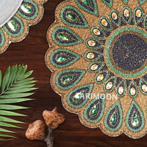 May include: A round beaded placemat with a peacock feather design in shades of gold, green, and blue. The placemat is made of small beads and sequins.