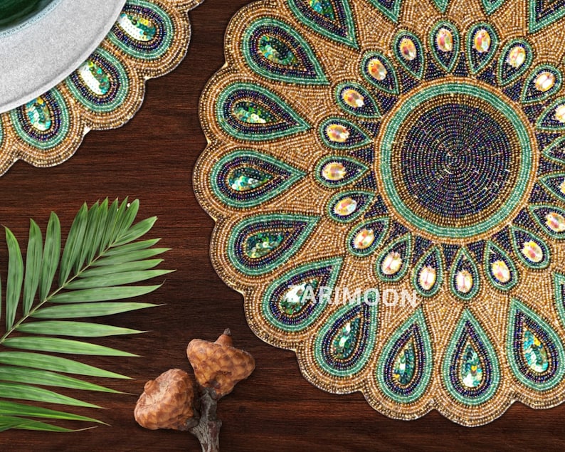 May include: A round beaded placemat with a peacock feather design in shades of gold, green, and blue. The placemat is made of small beads and sequins.