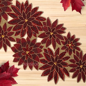 May include: A red and gold beaded table runner featuring a poinsettia design. The runner is crafted from small beads and has a festive Christmas feel.