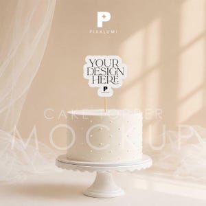 May include: A white cake topper with a scalloped edge featuring the black text YOUR DESIGN HERE and a small P logo, mounted on a thin wooden stick. The topper is positioned above a white cylindrical cake decorated with small white dots on a stand.