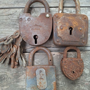 May include: Four vintage rusty padlocks with a set of keys. The padlocks are various shapes and sizes. The padlocks are on a wooden surface.