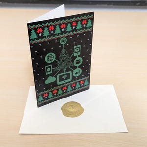 Könnte beinhalten: Eine Weihnachtskarte mit schwarzem Hintergrund und einem grünen und roten Muster. Die Karte zeigt ein Weihnachtsbaumdesign mit verschiedenen technologiebezogenen Symbolen. Die Karte steht auf einem weißen Umschlag mit einem goldenen Wachssiegel.
