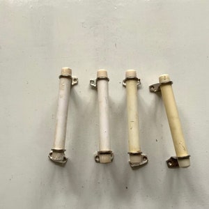 May include: Four white plastic cabinet door pulls with silver metal brackets.