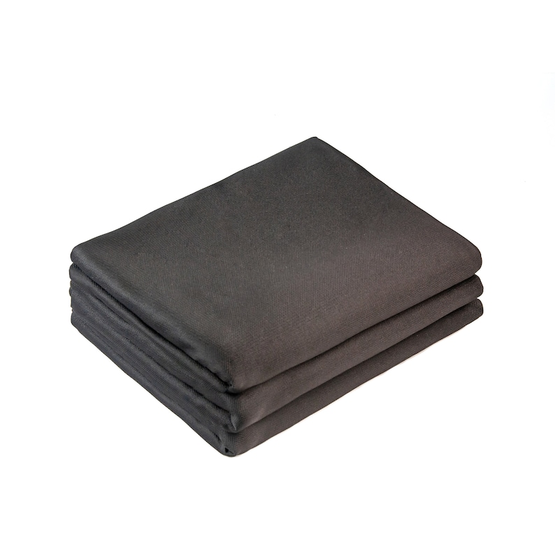 May include: A stack of three dark gray fabric placemats. The placemats are folded in half and stacked on top of each other.