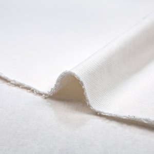 May include: Close-up of a white ribbed fabric folded over itself. The fabric is soft and has a slightly textured surface.