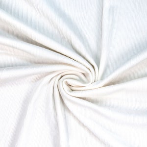 May include: White ribbed fabric with a soft, smooth texture. The fabric is folded and twisted, creating a swirling pattern.