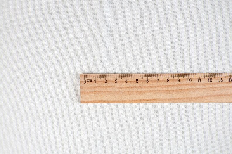 May include: A wooden ruler with black markings for centimeters and inches. The ruler is 15 centimeters long and has markings from 0 to 15.
