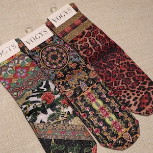 May include: Three pairs of patterned socks with the brand name "VOGYS" visible on the tags. The socks feature various designs, including floral, geometric, and animal print patterns in a range of colors like red, black, and gold.