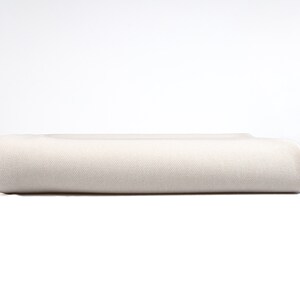 May include: A white, rolled-up fabric, possibly a blanket or sheet, with a smooth texture.
