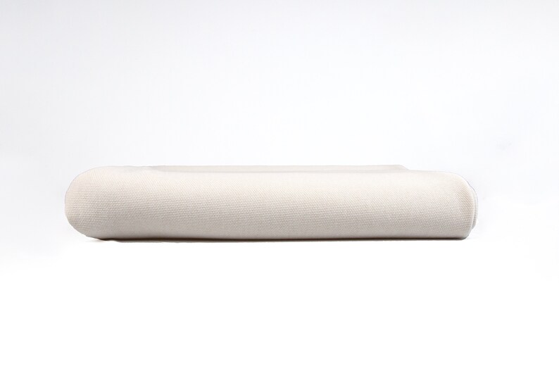 May include: A white, rolled-up fabric, possibly a blanket or sheet, with a smooth texture.