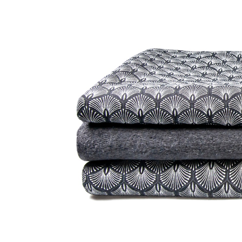 May include: A stack of three fabric swatches. The top and bottom swatches feature a black and white geometric pattern. The middle swatch is a solid dark gray.