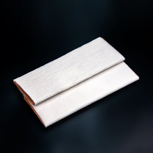 May include: Two white tissue paper sheets folded in half, with the edges of the paper slightly overlapping. The paper has a subtle texture and is folded in a way that creates a rectangular shape.