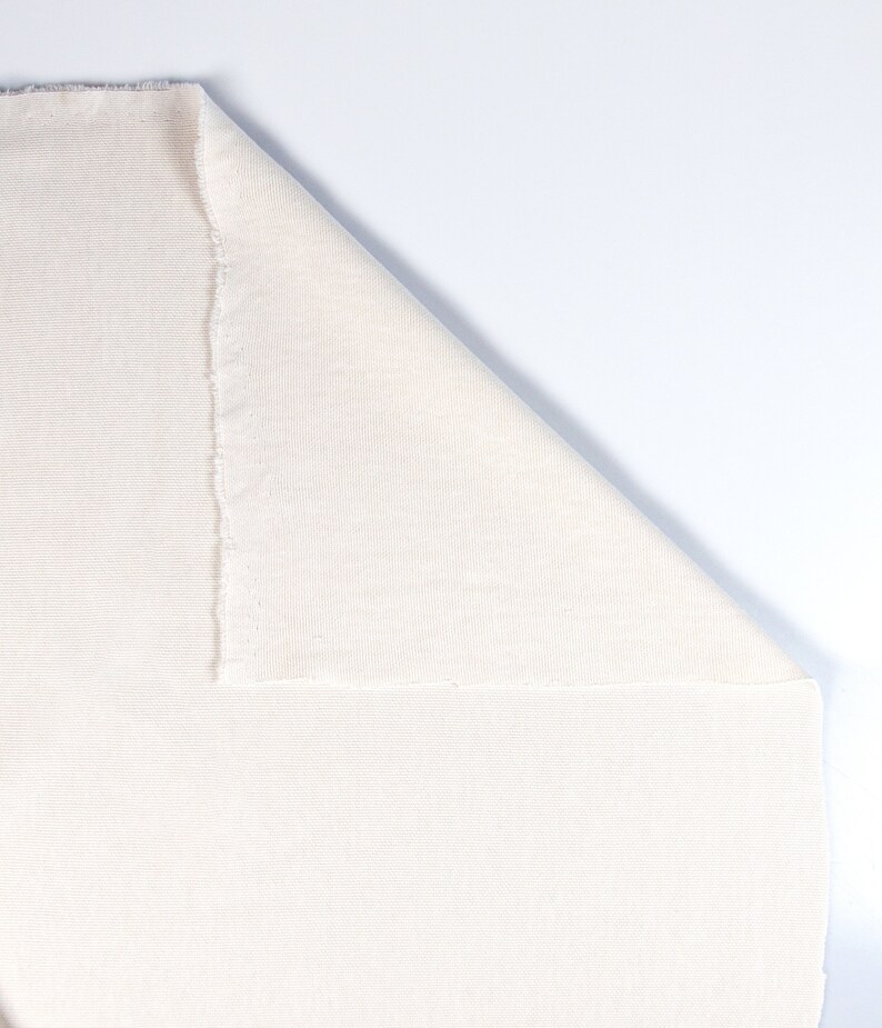 May include: A close-up of a white fabric with a ribbed texture. The fabric is folded in half, with one side folded over the other.