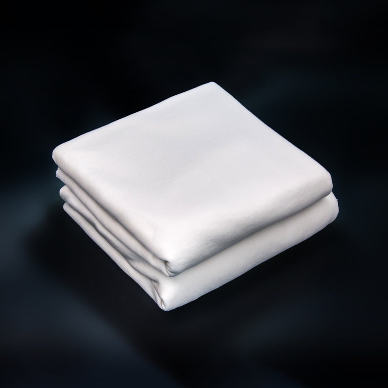 May include: A white cotton fitted sheet folded in half, showing the smooth texture of the fabric.