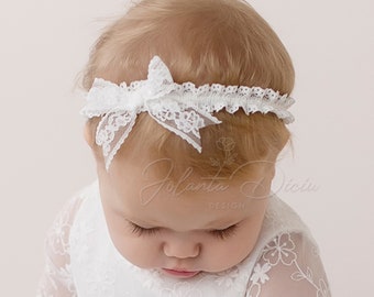 Bandeau bébé avec noeud en dentelle sur un élastique à volants de couleur blanc cassé, adapté pour un baptême, un anniversaire, un mariage, une séance photo.