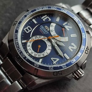 May include: A silver Orient Automatic 100m watch with a blue face and a silver band. The watch has a chronograph, a date window, and a tachymeter.