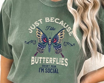 May include: Green t-shirt with a vintage-style graphic of a butterfly and the text "Just Because I Like Butterflies Doesn't Mean I'm Social."