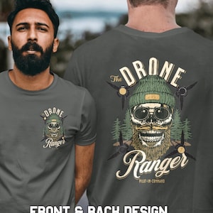 以下が含まれることがあります： ダークグリーンのTシャツに、ビーニーとサングラスをかけたスカルがプリントされています。スカルはあごひげと口ひげを生やしています。Tシャツには「The Drone Ranger Pilot-in-Command」と書いてあります。
