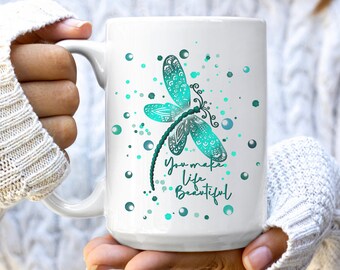 May include: White ceramic mug with a teal dragonfly design and the text "You make life beautiful". The dragonfly has intricate details and is surrounded by teal and white dots.