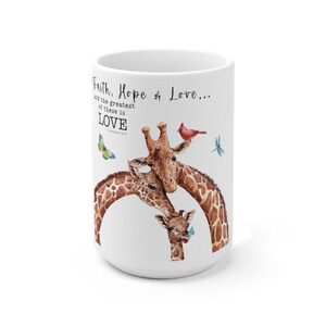 Puede incluir: Taza de cerámica blanca con una ilustración de acuarela de tres jirafas con manchas marrones y beige. La taza tiene el texto "Faith, Hope & Love... and the greatest of these is LOVE" con una mariposa, un cardenal y una libélula.