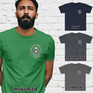 May include: A green, heather navy, and charcoal t-shirt with a skull and eagle graphic. The graphic says "Commercial Drone Pilot AKA Pro Bird  Douche".