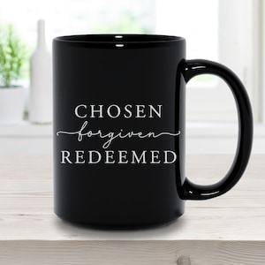 以下が含まれることがあります： 白い文字で「CHOSEN forgiven REDEEMED」と書かれた黒いセラミック製のコーヒーカップです。