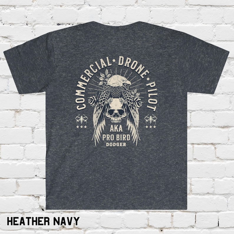 May include: Heather navy blue t-shirt with a graphic of a skull with wings and the text "Commercial Drone Pilot AKA Pro Bird Dodger".