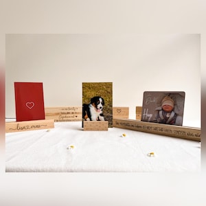 Könnte beinhalten: Eine Sammlung von Holz-Fotorahmen und dekorativen Blöcken. Die Fotorahmen zeigen einen Welpen, ein Baby und eine rote Karte mit einem Herzen. Einige Blöcke haben Text und Herz-Designs.