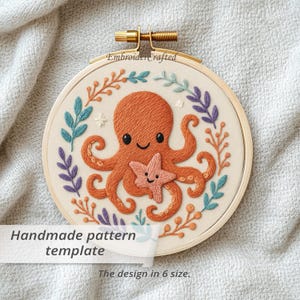 以下が含まれることがあります： 木製のフープに刺繍されたタコとヒトデのデザイン。タコはオレンジ色で笑顔、ヒトデはピンク色です。デザインは、青、紫、オレンジの色合いの刺繍された葉と枝に囲まれています。「Handmade pattern template」と書かれたテキスト。