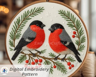 May include: A digital embroidery pattern featuring two embroidered birds with red breasts, gray wings, and black heads, perched on a branch with red berries. The design is framed by a wooden hoop and surrounded by green pine needles. The text "Digital Embroidery Pattern" is visible.