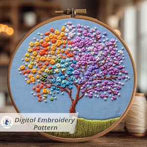 May include: A colorful, hand-stitched embroidery of a tree with rainbow-colored leaves. The tree is set against a light blue fabric, framed in a wooden hoop. The text "Digital Embroidery Pattern" is visible.