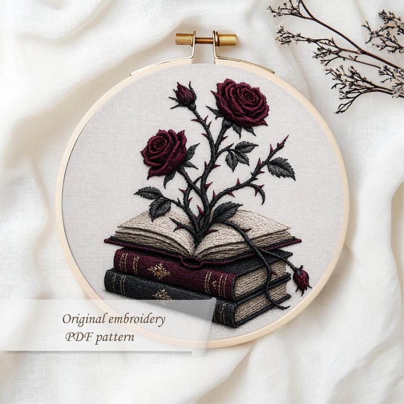 May include: Embroidered design of burgundy roses and thorns emerging from a stack of books. The embroidery is set in a wooden hoop. The text "Original embroidery PDF pattern" is at the bottom.